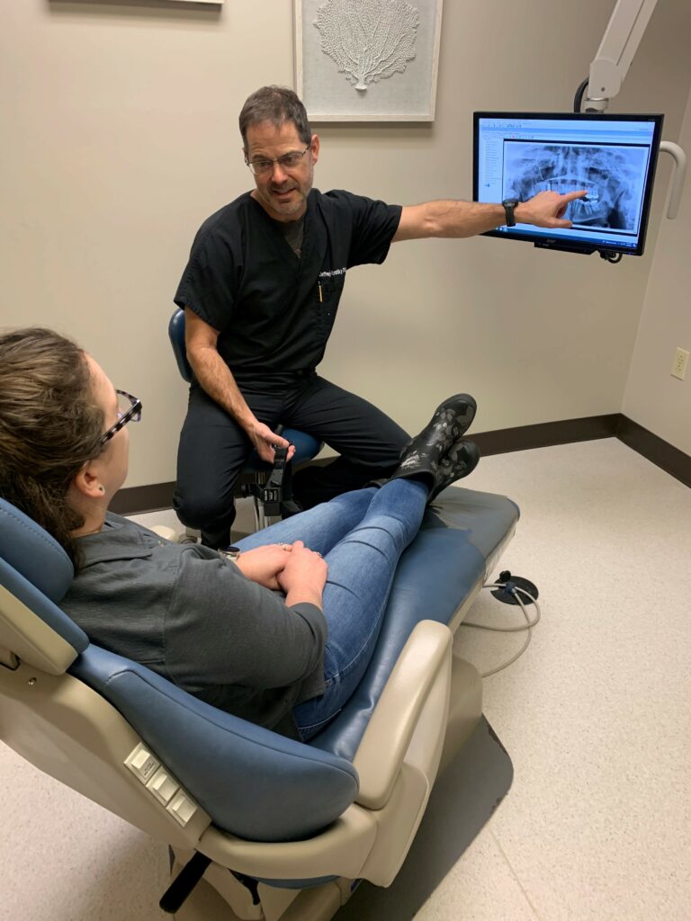 Dr Kratky an Oral Surgeon at Midwest Oral Maxillofacial & Implant showing a patient their xrays