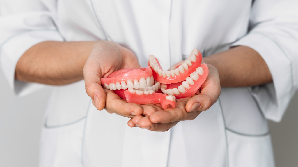 an oral surgeon holds dentures in their hands