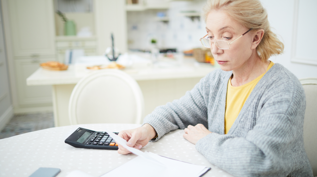 A woman looking at a paper with a calculator next to her
