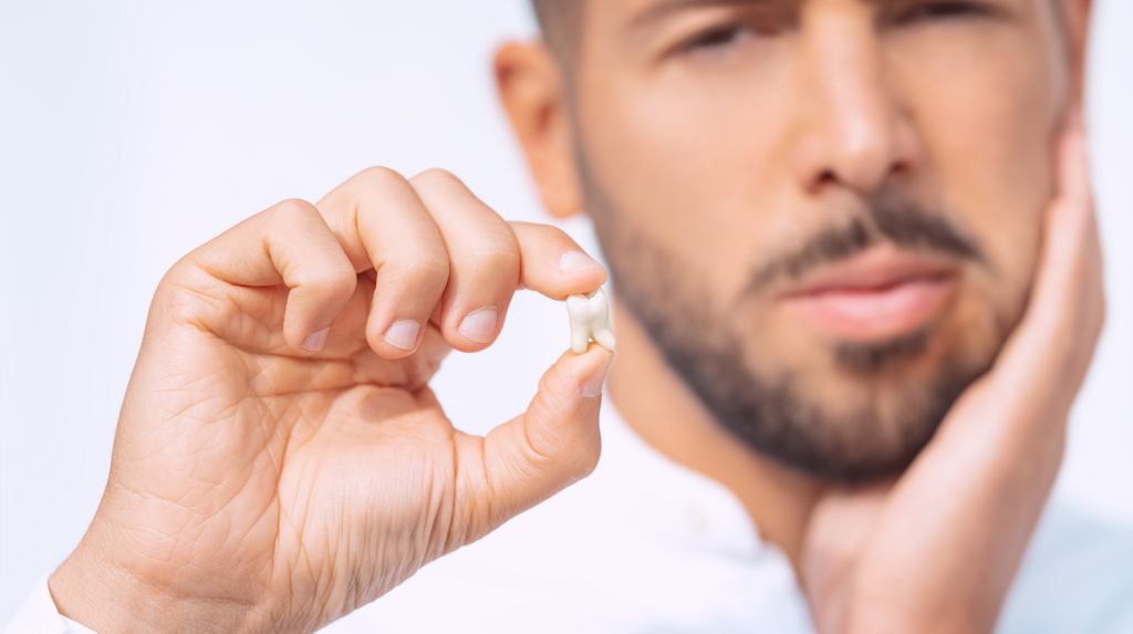 Man holding a tooth as an example to oral pain